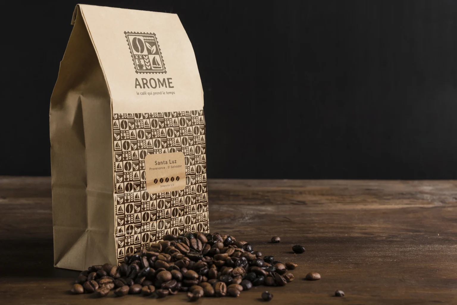 un sachet de cafés de la marque Arome posé sur une table avec quelques grains de cafés devant le sachet