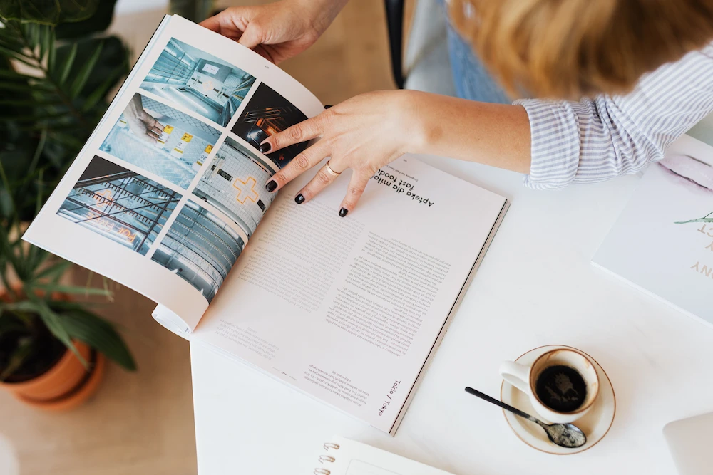une femme lisant de la documentation sur une brochure avec un café, en vue du dessus