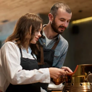 une femme et un homme se tenant côte à côte en train de régler une machine à café
