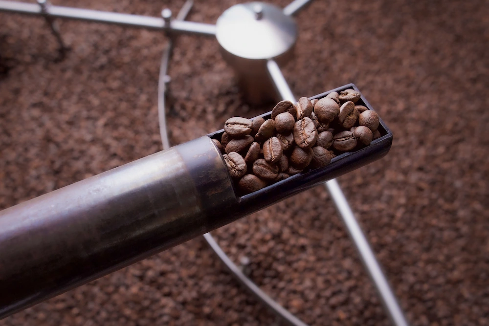 vue sur un bras métallique contenant des grains de café, provenant d'une machine à torréfier le café