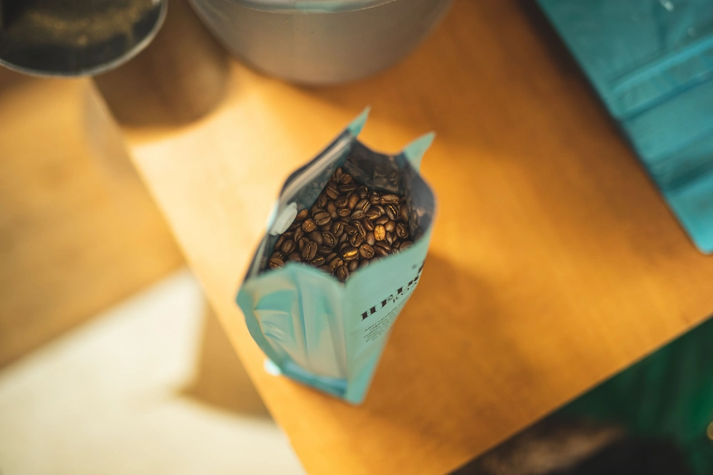un sachet de café ouvert vue du dessus laissant entrevoir les grains de café dedans